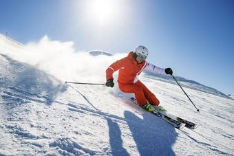 Skifahrerin auf der Piste bei sonnigem Wetter schaut in die Kamera.